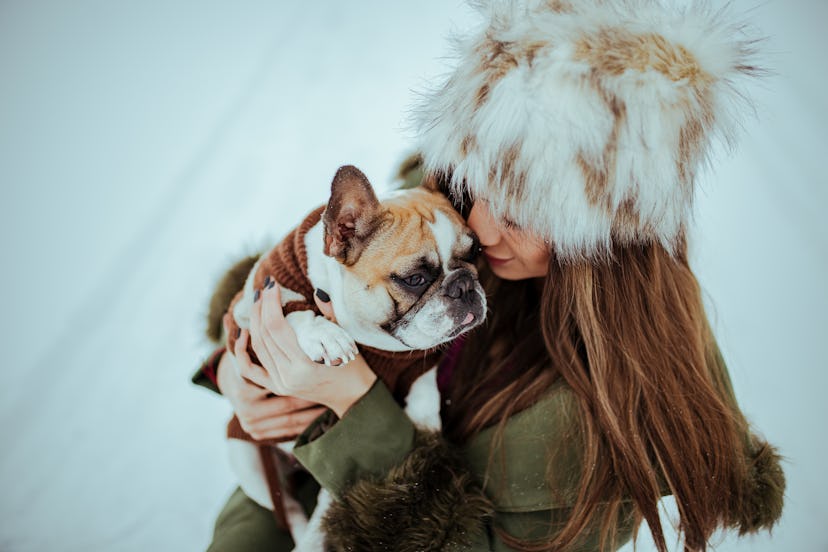 A woman hugs her dog in the snow. Scientists disagree about how cooler temperatures might affect bra...