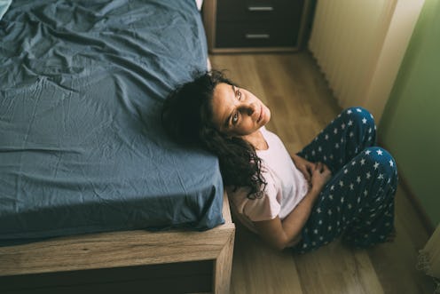 A woman sits by a bed. Menopause is a complex process that involves the slowdown of estrogen product...