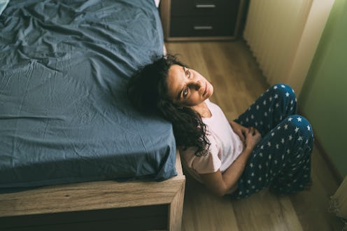 A woman sits by a bed. Menopause is a complex process that involves the slowdown of estrogen product...