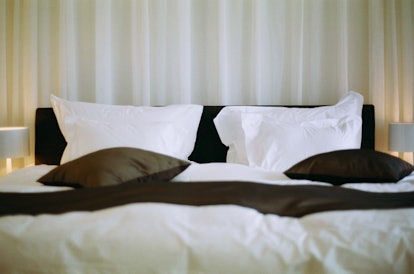 A made bed with white bedding and black-trimmed pillows and sheets. If you're allergic to bird feath...