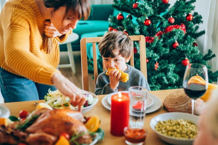 a family eating Thanksgiving dinner with a Christmas tree in the background