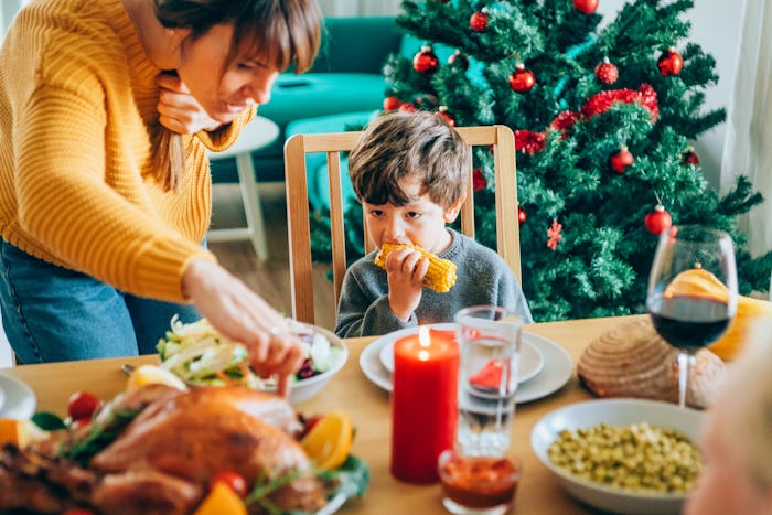 a family eating Thanksgiving dinner with a Christmas tree in the background