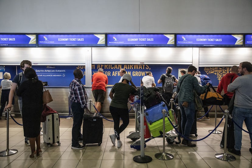 People wait in line at an airport. Flu germs can transmit easily in crowded spaces in airports. 