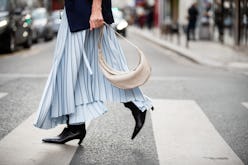 A woman crossing a street in a light blue dress