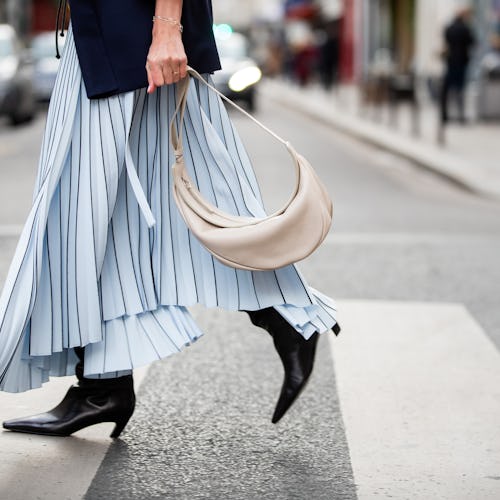 A woman crossing a street in a light blue dress