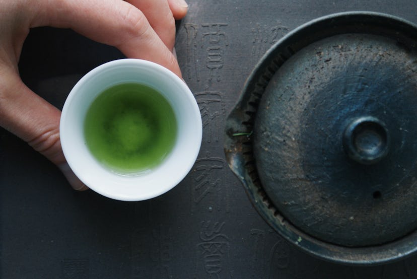 Green tea in a ceramic bowl beside a teapot. Swapping green tea for morning coffee may improve the b...