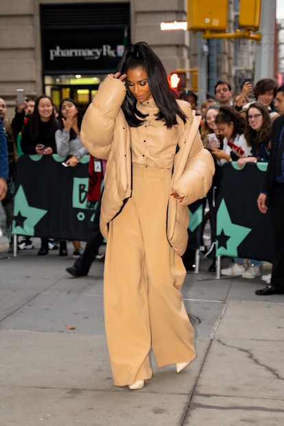 Ciara walking in a light brown jacket, light brown leather shirt, and in light brown pants