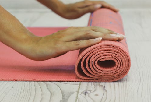 A person rolls up a yoga mat. Yoga poses can trigger gender dysphoria