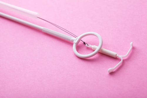 An IUD on a pink background. Here's what an OBGYN wants you to know if your IUD has moved