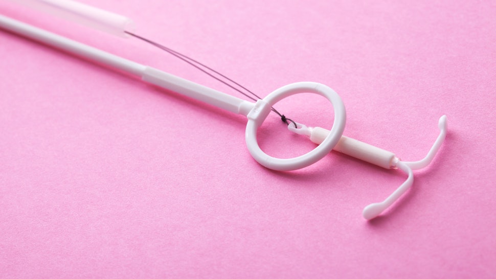 An IUD on a pink background. Here's what an OBGYN wants you to know if your IUD has moved