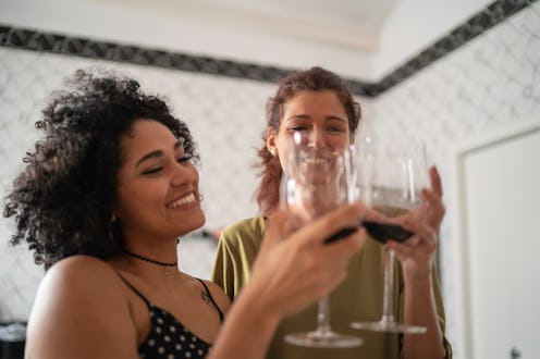 Two women toast each other with wine. Experts tell Bustle what you should know if your partner and y...