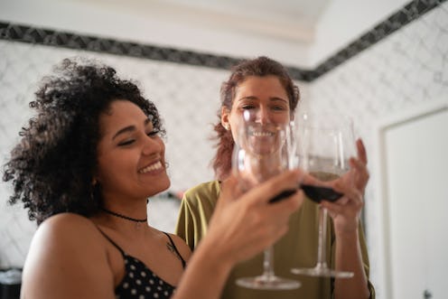 Two women toast each other with wine. Experts tell Bustle what you should know if your partner and y...