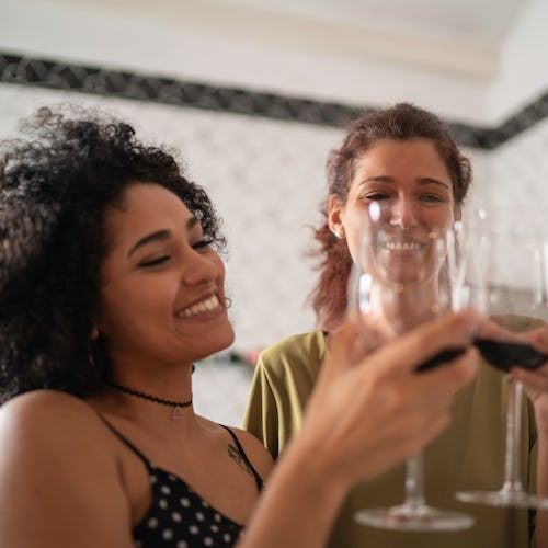 Two women toast each other with wine. Experts tell Bustle what you should know if your partner and y...