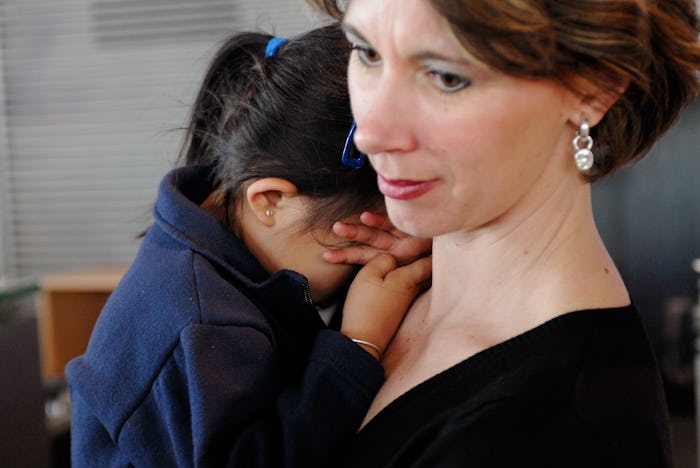 A picture of a woman holding a young toddler, crying on her shoulder.
