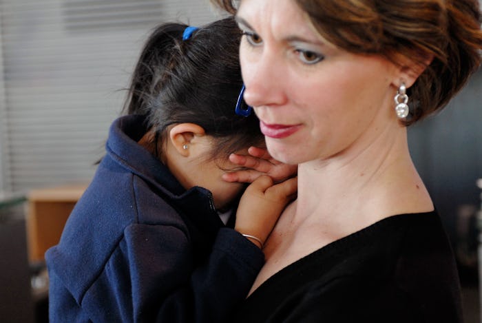 A picture of a woman holding a young toddler, crying on her shoulder. 