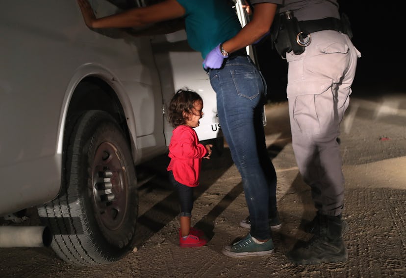 A picture of a young immigrant child, crying, while her parent is being searched by a border patrol ...