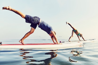 Two people doing paddleboard yoga. One of the fitness trends of the last decade was, funnily enough,...