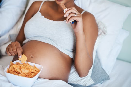 a pregnant woman snacking in bed