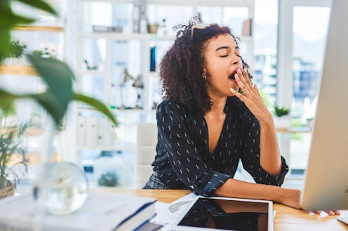 A woman yawns in front of her computer. Burnout affects your brain in key ways, an expert tells us.