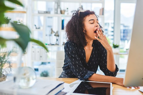 A woman yawns in front of her computer. Burnout affects your brain in key ways, an expert tells us.