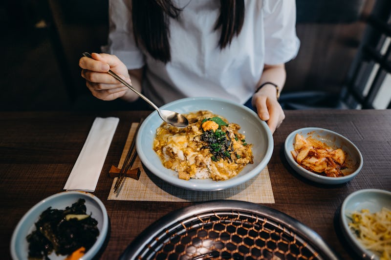 A woman eats a plate of eggs. Eating more protein than your body needs can lead to adverse health ef...