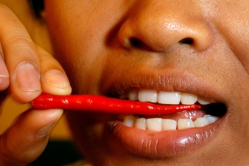 A woman bites a chili pepper. The food was linked to a reduced risk of death from heart disease in a...