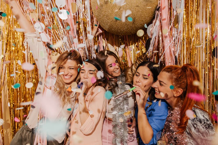 A group of friends party under confetti on New Year's Eve.