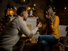 A guy proposes to his girlfriend in their family room on New Year's Eve.