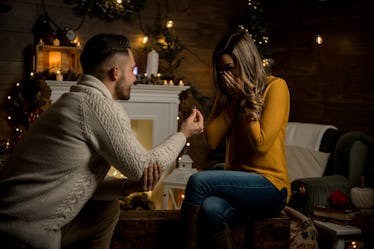 A guy proposes to his girlfriend in their family room on New Year's Eve.