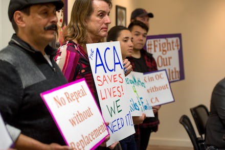 A group of people holding posters in protest against Obamacare being on the chopping block - again