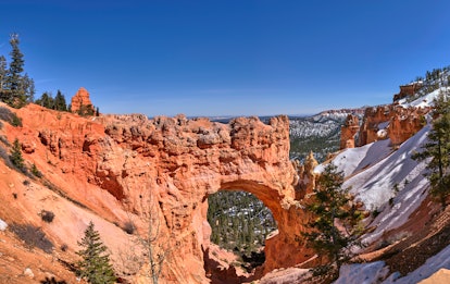 Bryce Canyon National Park in Utah is covered with snow on a sunny day in the middle of winter.