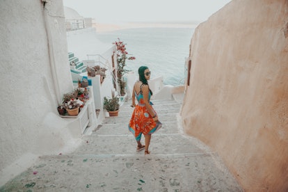 A woman walks down stairs toward the ocean while on an underrated family vacation in Santorini, Gree...