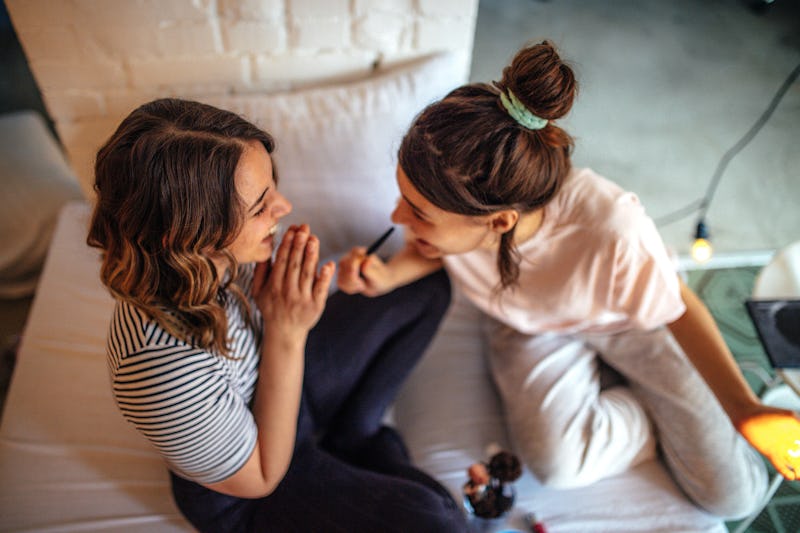 Two women in their pajamas do their makeup before a night of staying in.