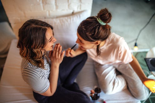 Two women in their pajamas do their makeup before a night of staying in.