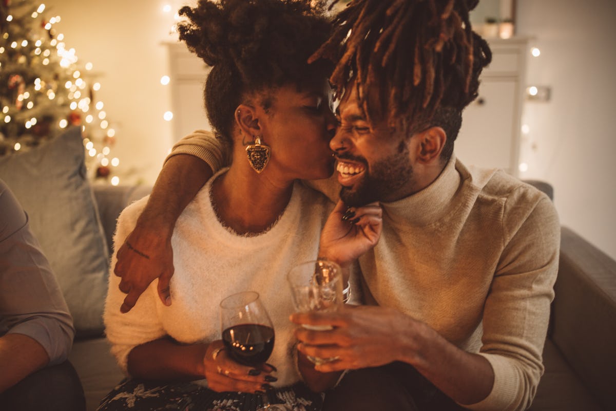 A couple cuddles on the couch with drinks on their hand on New Year's Eve.