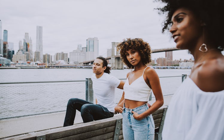 Three friends pose near the Brooklyn Bridge when visiting New York City for a day.