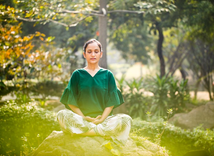 a woman sitting cross-legged on a rock meditating