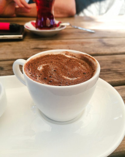 A cup of hot chocolate sits on a wood table.