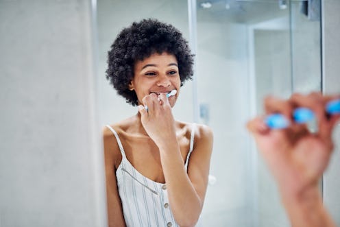 A person brushes their teeth in the mirror. Brushing teeth was linked to better heart health in a 20...