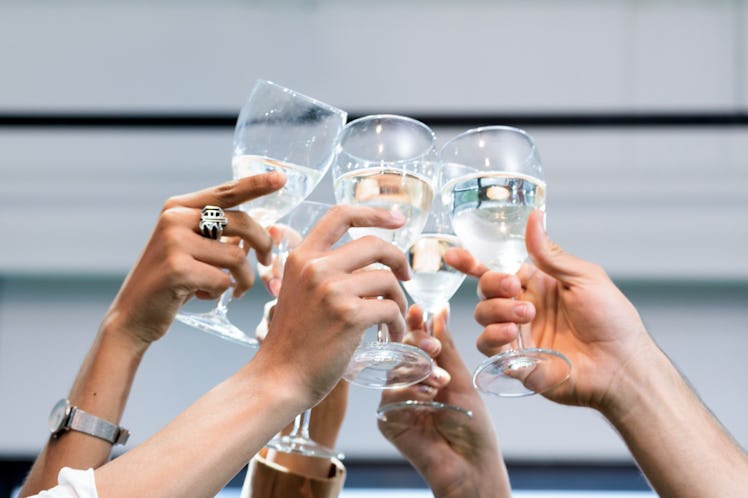 A group of friends holds up their glasses of champagne on New Year's Eve.
