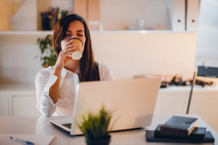 woman drinking coffee at desk at work
