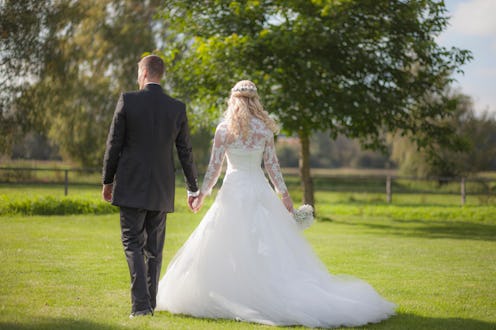 A bride and groom in a stock image walk through a field. Content that romanticizes plantation weddin...
