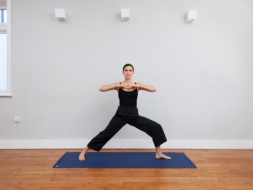 Adriene Mishler of Yoga with Adriene poses on a blue mat in a yoga studio. Gender-neutral language i...