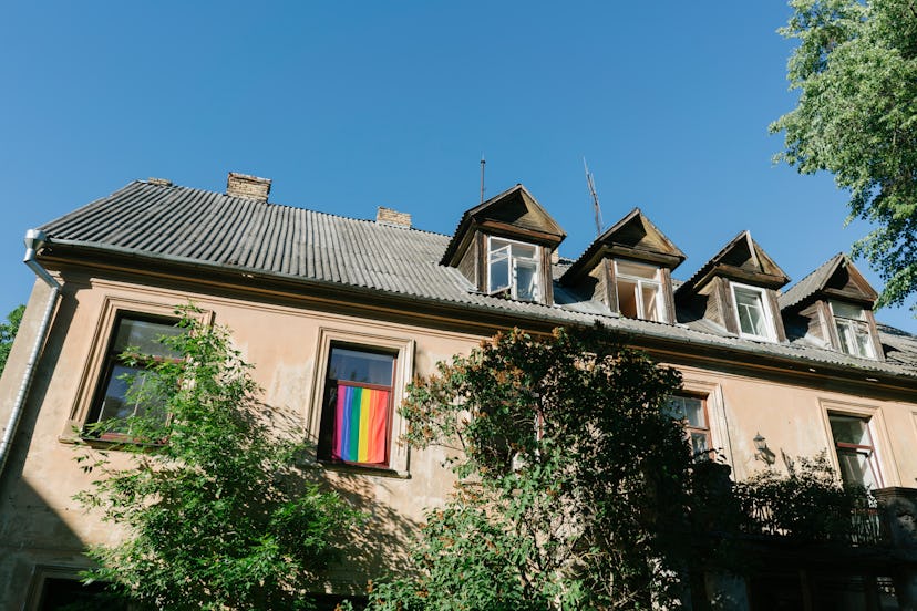 A rowhouse with a pride flag hanging from a window. LGBTQ housing discrimination is still legal, but...