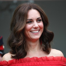 Kate Middleton in a red dress, smiling while posing for a photo