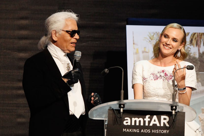 Diane Kruger standing next to Karl Lagerfeld on stage while he is giving a speech
