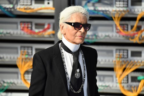 Karl Lagerfeld wearing his signature black suit with a tie, and black shades