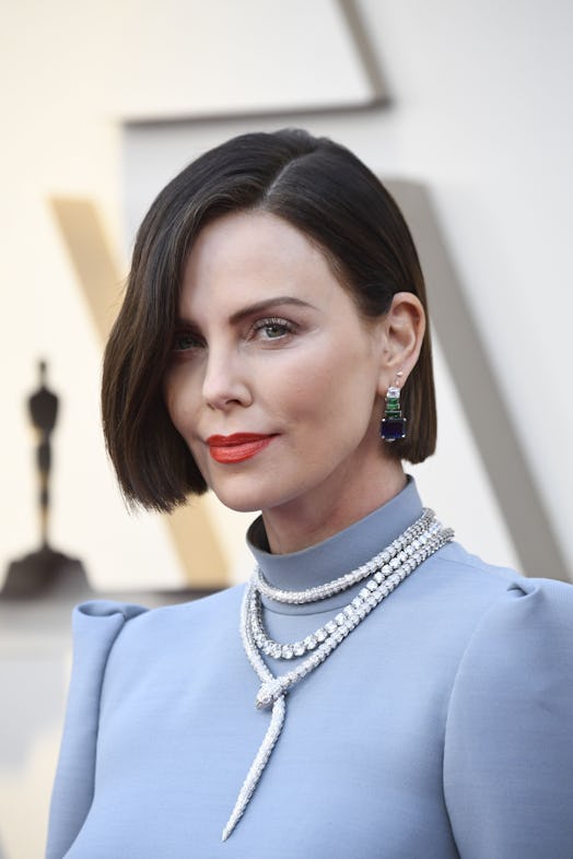Charlize Theron with short brunette hair in a light blue high-neck dress and pearls 