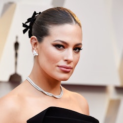 Ashley Graham at the 2019 Oscars in a strapless black dress with her hair up in black bows