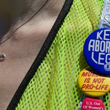 A woman wearing a neon green vest with badge reading: 'Keep abortion legal.'